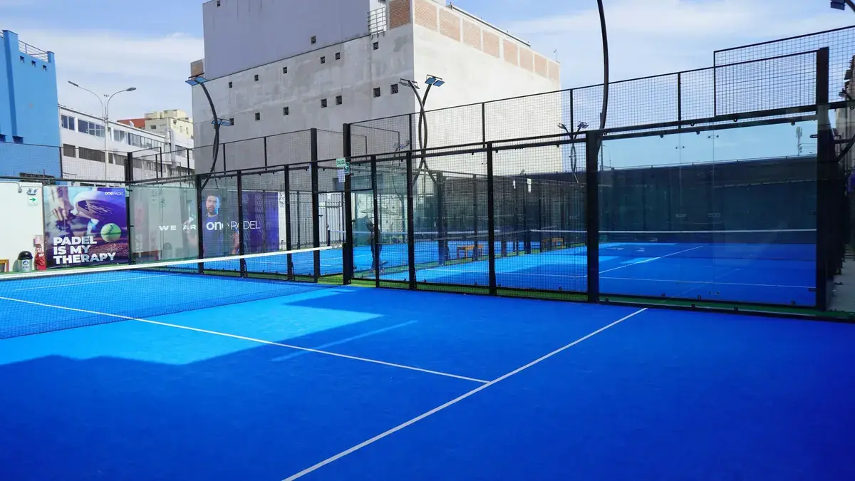 Pista de pádel exterior con paredes de cristal y césped azul