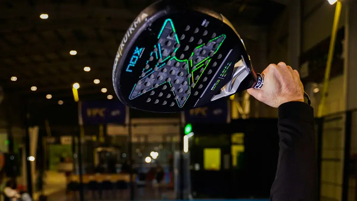 Jugador levantando una pala de pádel Nox en una pista cubierta