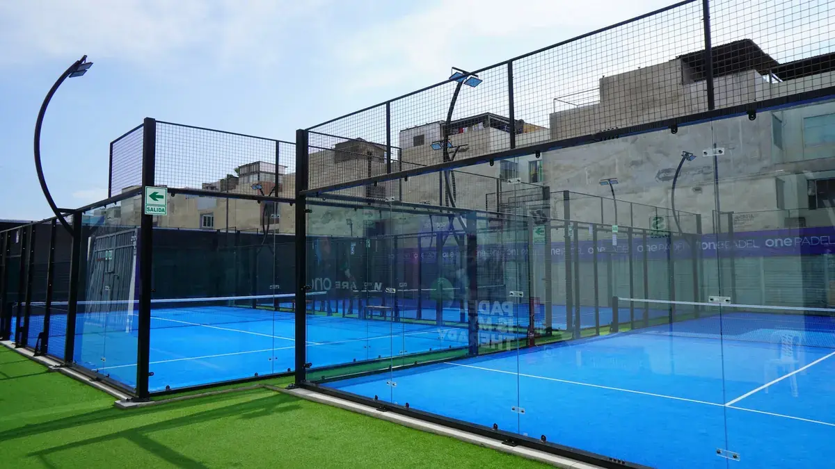 Pistas de pádel exteriores con paredes de cristal y césped azul
